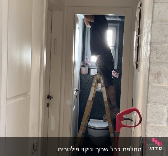 אדם על סולם מתקן מיזוג אוויר בתקרה